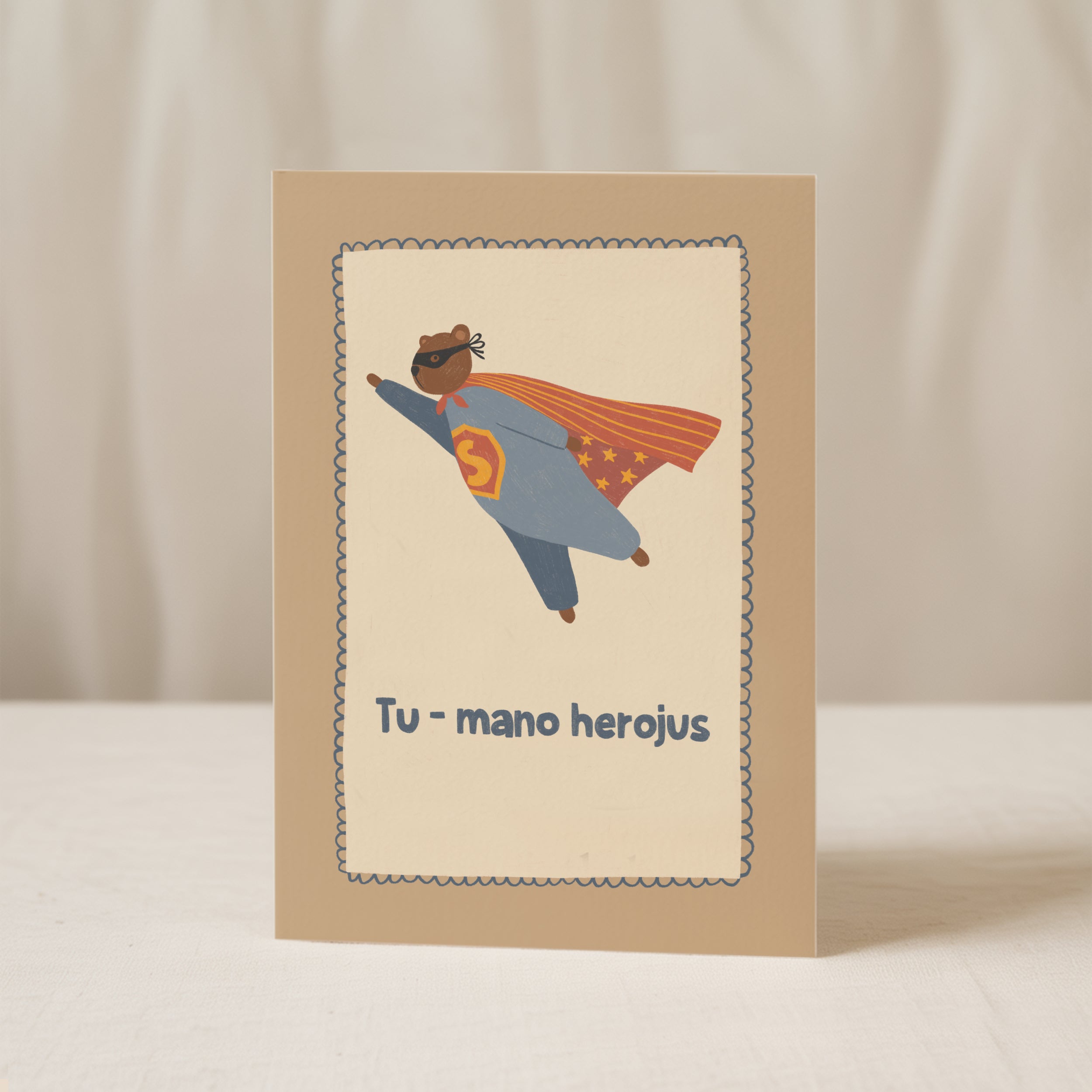Cute greeting card featuring a teddy bear flying like a superhero with the text “Tu – mano herojus” below, whimsical hero-themed illustration.