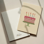 Funny birthday greeting card featuring an illustrated cake with candles and the word "KIEK?" instead of candle flames, humorous minimalist birthday design.