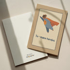 Cute greeting card featuring a teddy bear flying like a superhero with the text “Tu – mano herojus” below, whimsical hero-themed illustration.