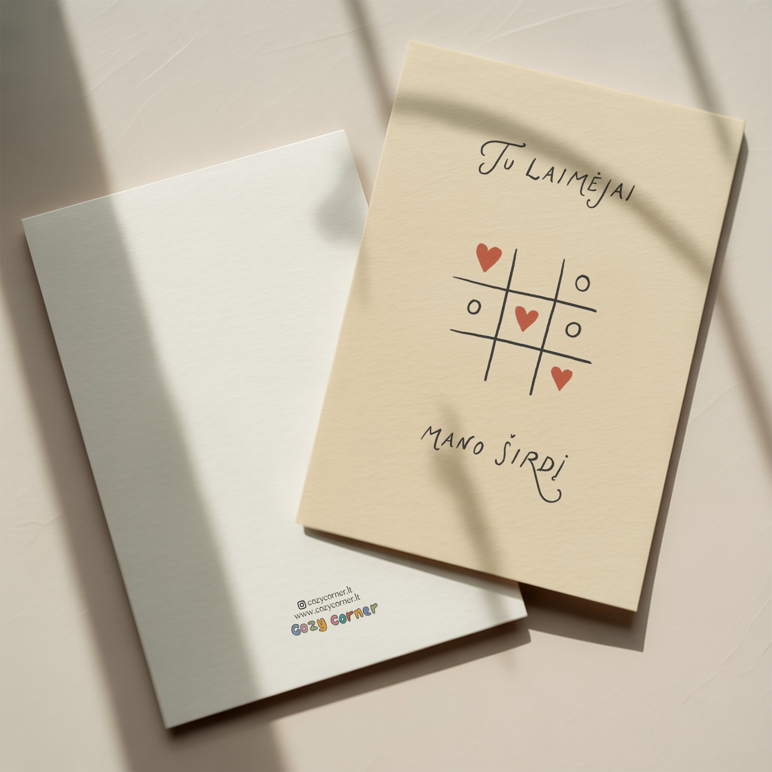 Romantic greeting card featuring a tic-tac-toe game with heart symbols instead of X and O, and the phrase “Tu laimėjai mano širdį” written below.