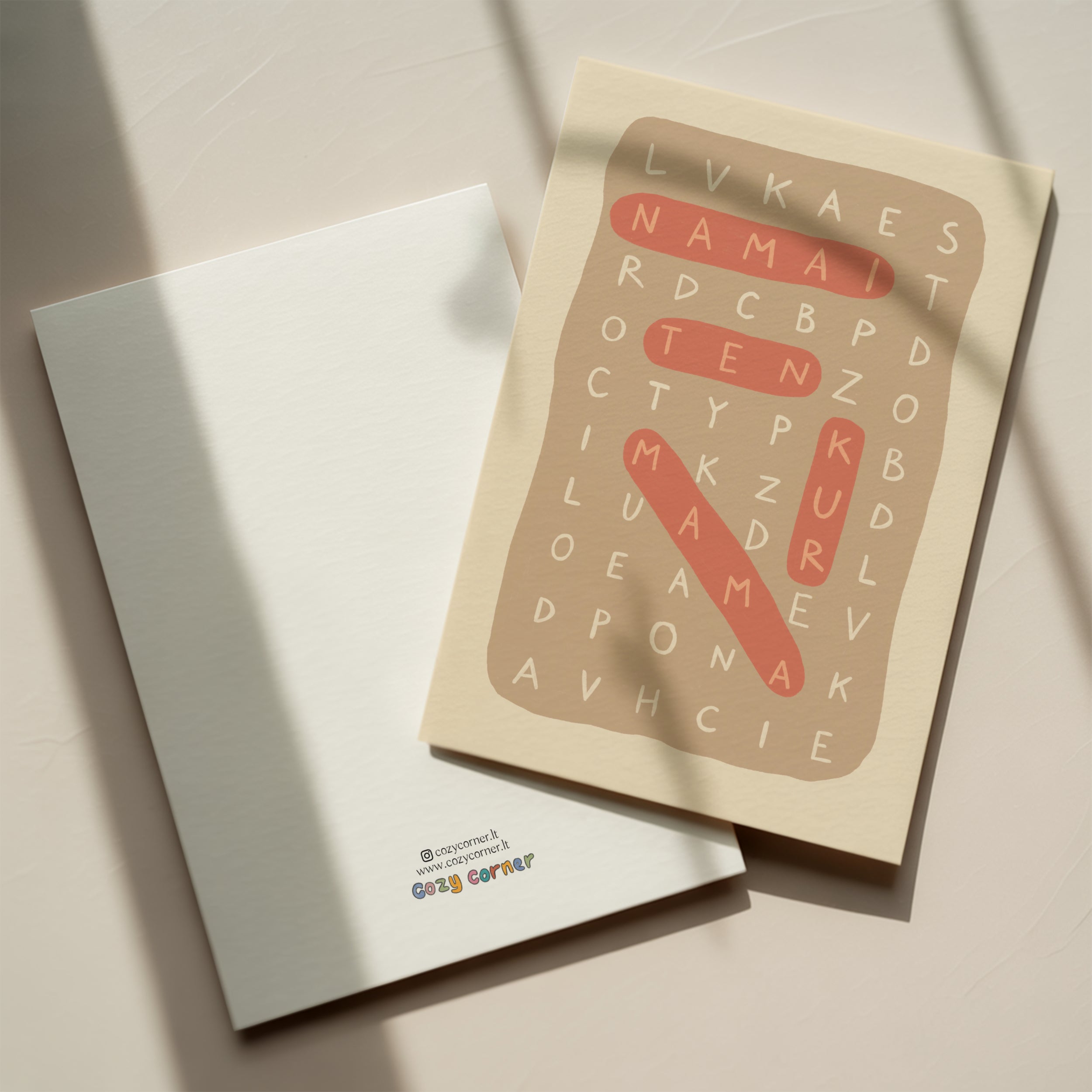 Minimalist greeting card featuring a letter puzzle crossword design with highlighted words “Namai ten kur mama” on a clean white background.