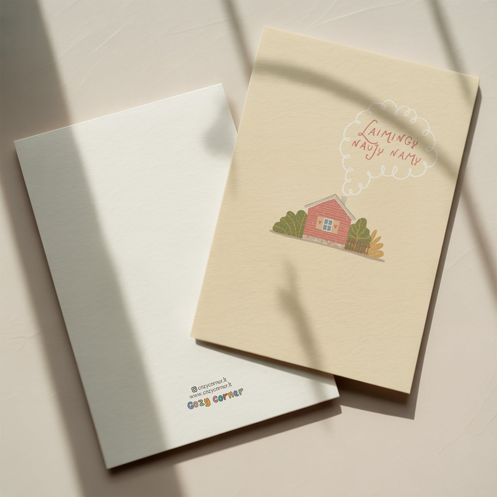 Cozy housewarming greeting card featuring an illustrated cottage with chimney smoke forming the words “Laimingų naujų namų”, warm new home celebration design.