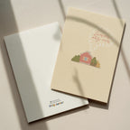 Cozy housewarming greeting card featuring an illustrated cottage with chimney smoke forming the words “Laimingų naujų namų”, warm new home celebration design.