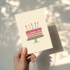 Funny birthday greeting card featuring an illustrated cake with candles and the word "KIEK?" instead of candle flames, humorous minimalist birthday design.