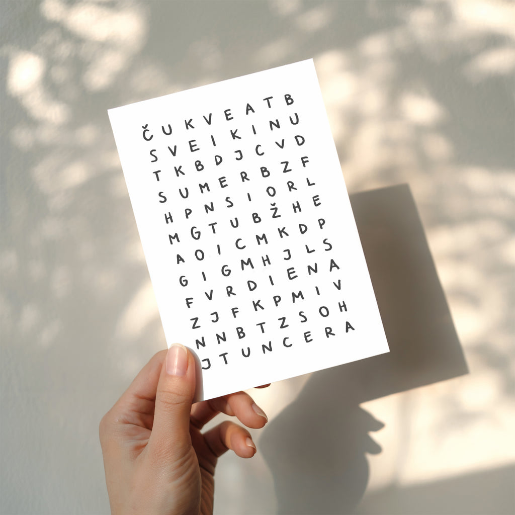 Minimalist birthday greeting card featuring a crossword-style letter puzzle with the hidden message “Sveikinu su gimimo diena” on a white background.