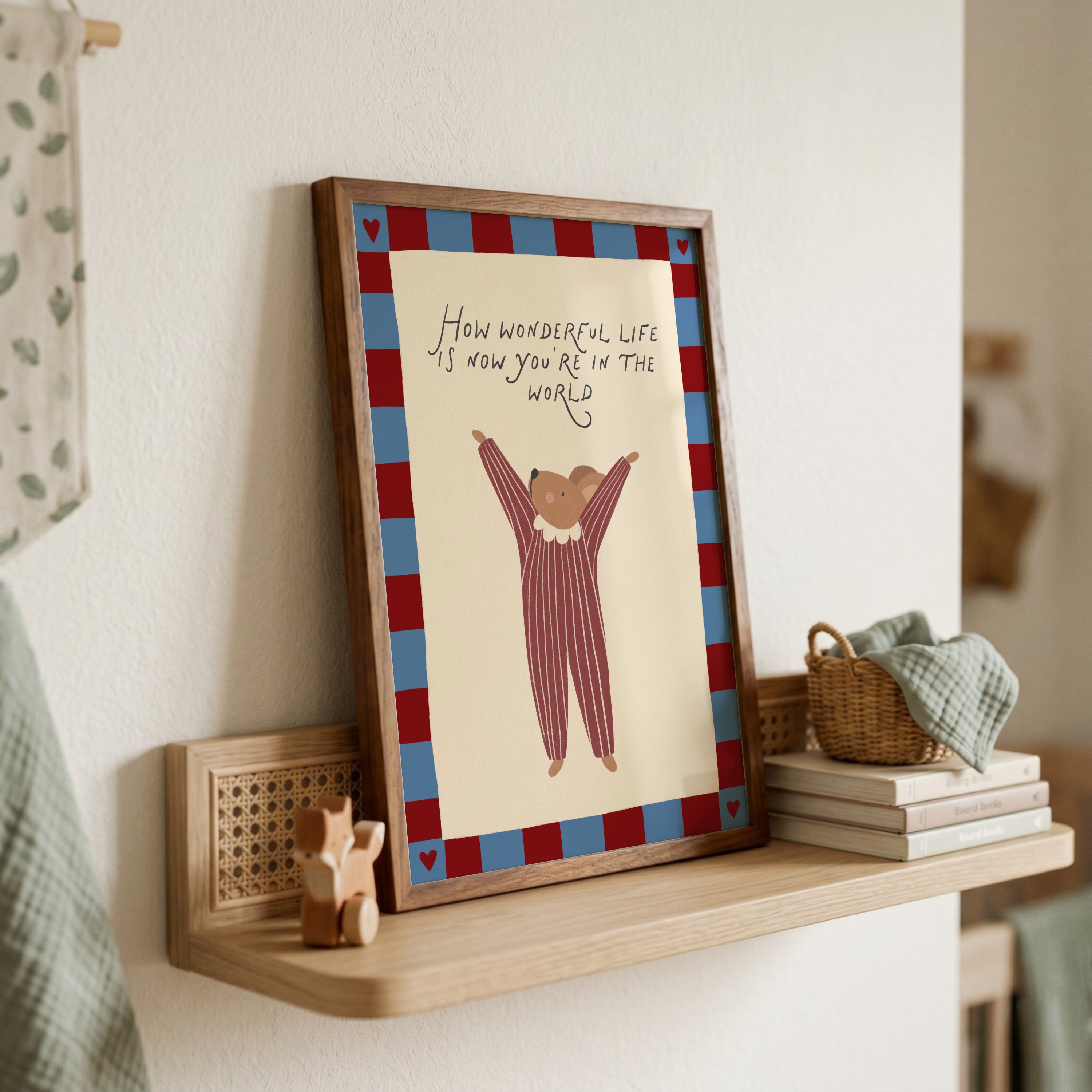 Cute storybook mouse wearing a striped outfit, standing with arms raised and pointing toward the quote "How wonderful life is now you're in the world". Beige background with a blue and burgundy gingham-style border, printable nursery wall art.