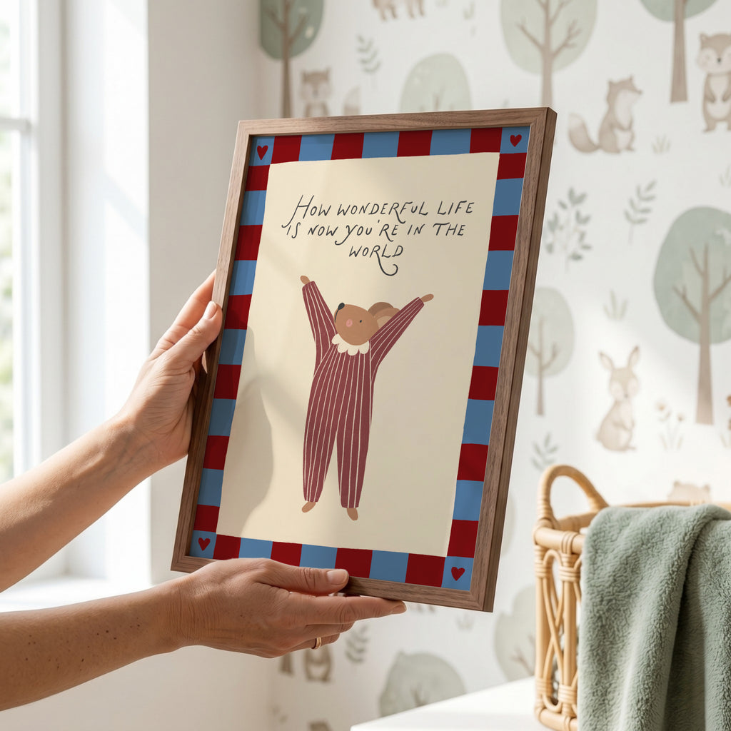 Cute storybook mouse wearing a striped outfit, standing with arms raised and pointing toward the quote "How wonderful life is now you're in the world". Beige background with a blue and burgundy gingham-style border, printable nursery wall art.