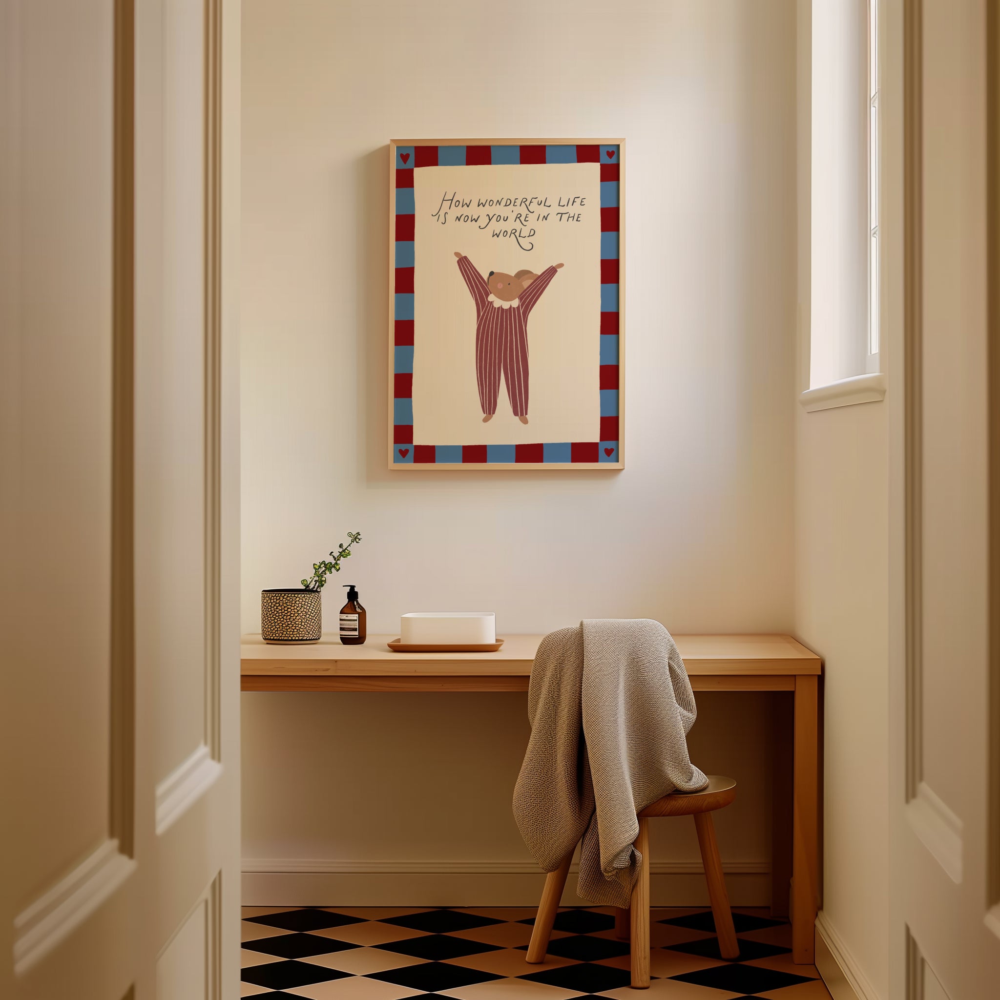 Cute storybook mouse wearing a striped outfit, standing with arms raised and pointing toward the quote "How wonderful life is now you're in the world". Beige background with a blue and burgundy gingham-style border, printable nursery wall art.