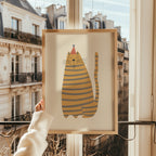 Cute kids wall art featuring a yellow striped cat with blue stripes wearing a small hat, illustrated in a soft minimalist style on a warm beige background, printable digital artwork for nursery, playroom, or kids room decor, designed to create a cozy, calm, and playful interior atmosphere.